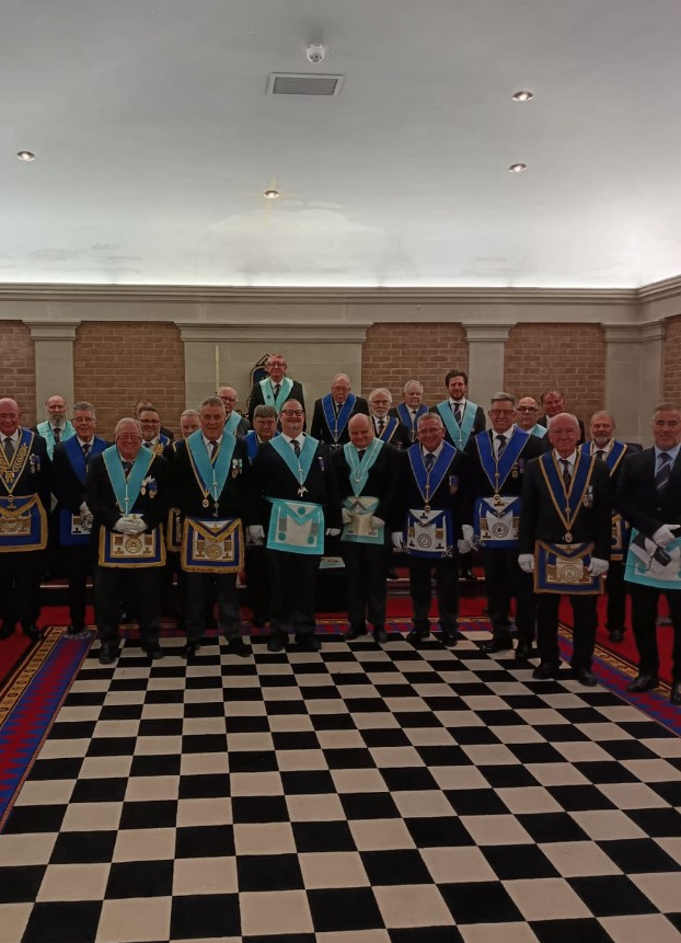 Large group of Brethren in Masonic regalia on the checkered lodge floor